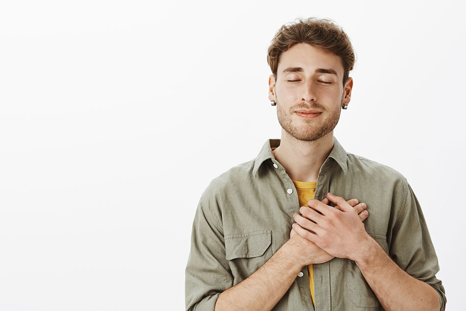 Someone with a hand over their chest, eyes closed — soft lighting, peaceful expression.
