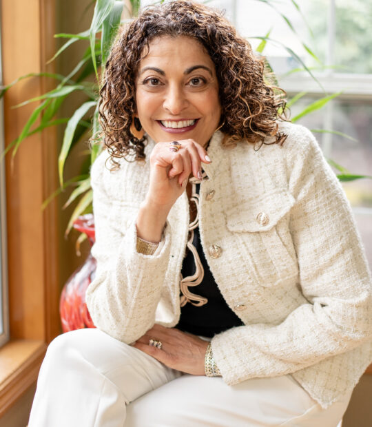 Dorice Horenstein sitting near the window, smiling gracefully.