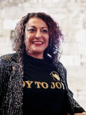 Dorice Horenstein smiling in a sparkly jacket, representing Jewish coaching and Hebrew learning